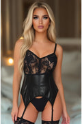 Woman wearing a black lace and leather bodysuit in a softly lit room.