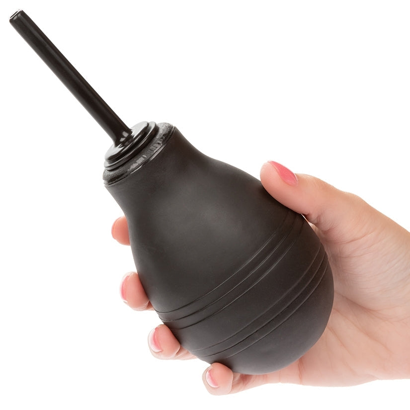 Black rubber bulb syringe held in a hand against a white background