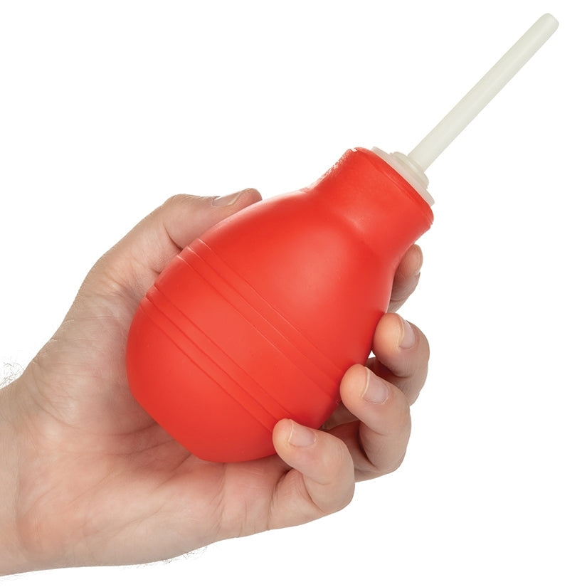 Red bulb syringe held in a hand against a white background
